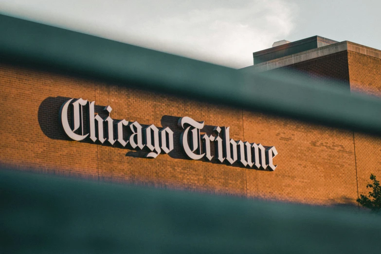 a chicago tribune sign is seen through the back gate of an office building