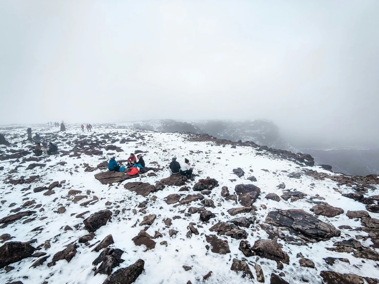 people sitting on top of a rocky mountain covered in snow