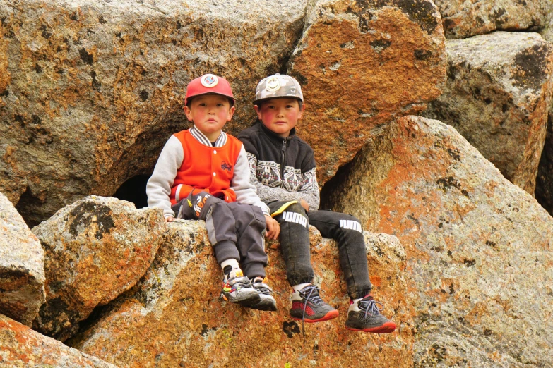 two children are sitting on large rocks together