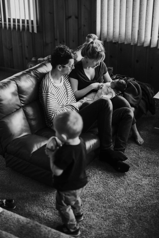 black and white image of a woman with her son sitting on a leather couch