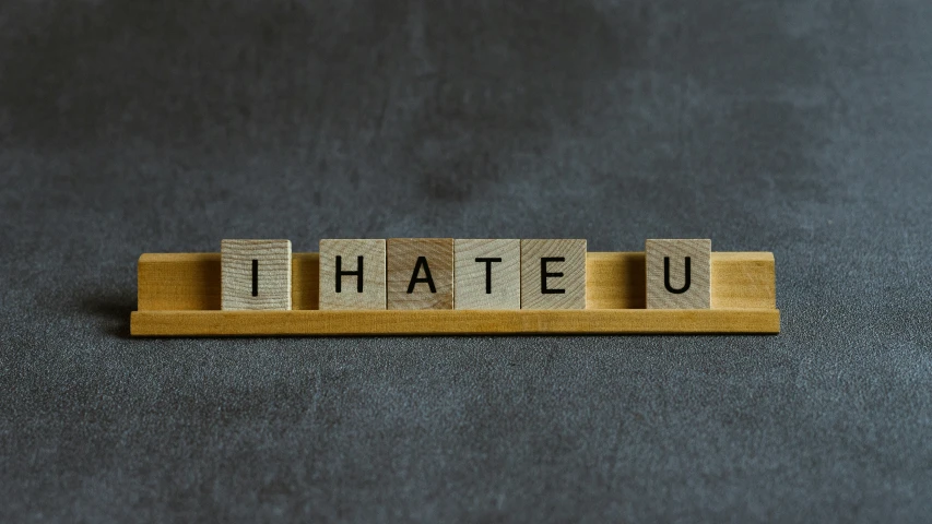 a scrabble wood block spelling the word i hate u