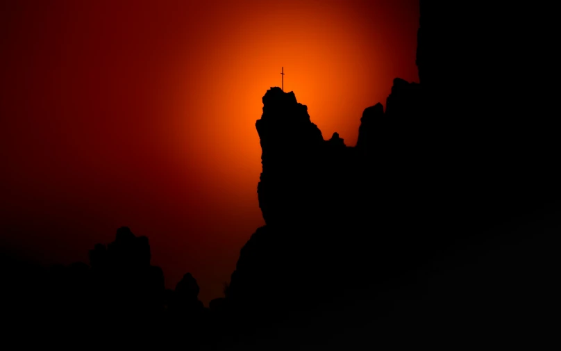 a silhouette of a building at sunset with sun behind it