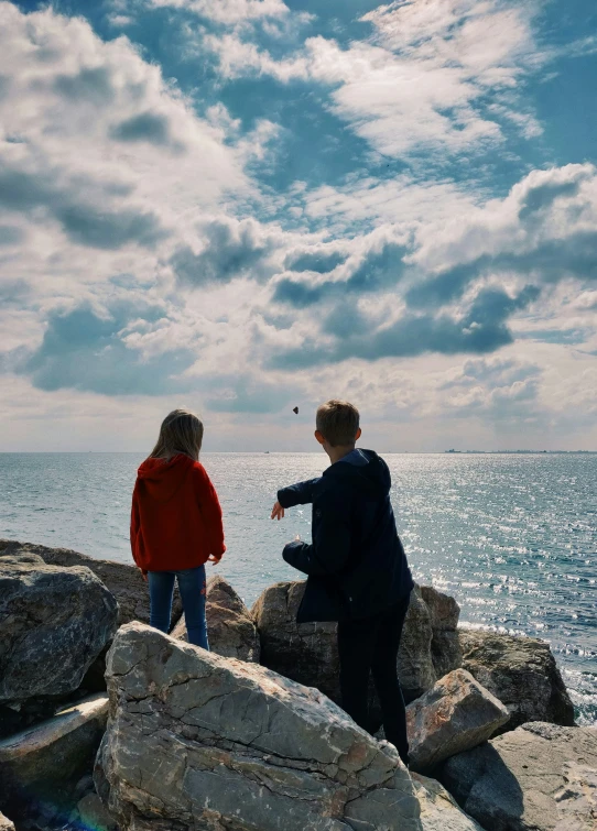 the two people are standing on rocks by the ocean