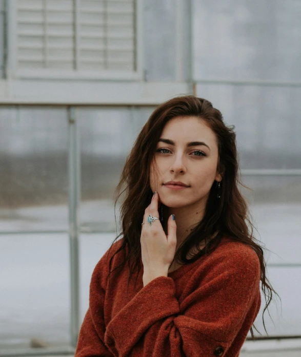 a woman in a red sweater is holding her finger to her ear