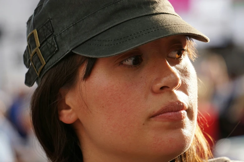 a woman looking away from the camera while wearing a green hat