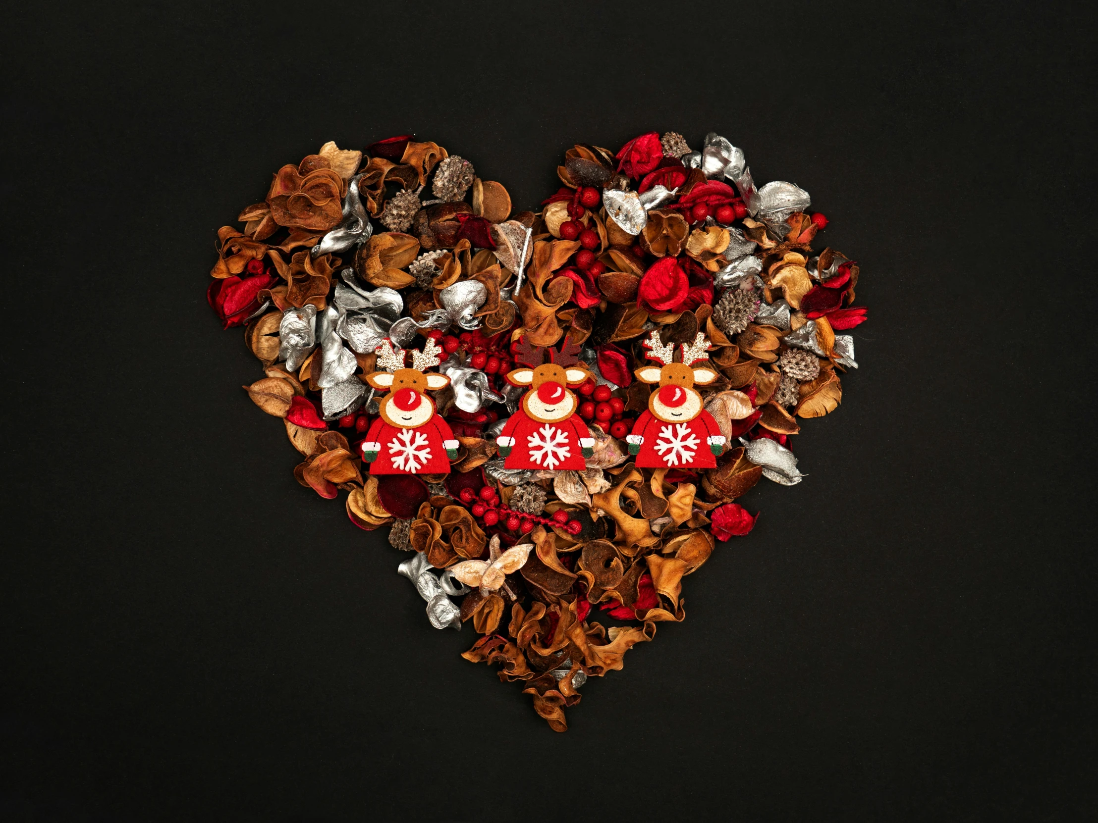a heart - shaped composition of flowers and other holiday decorations