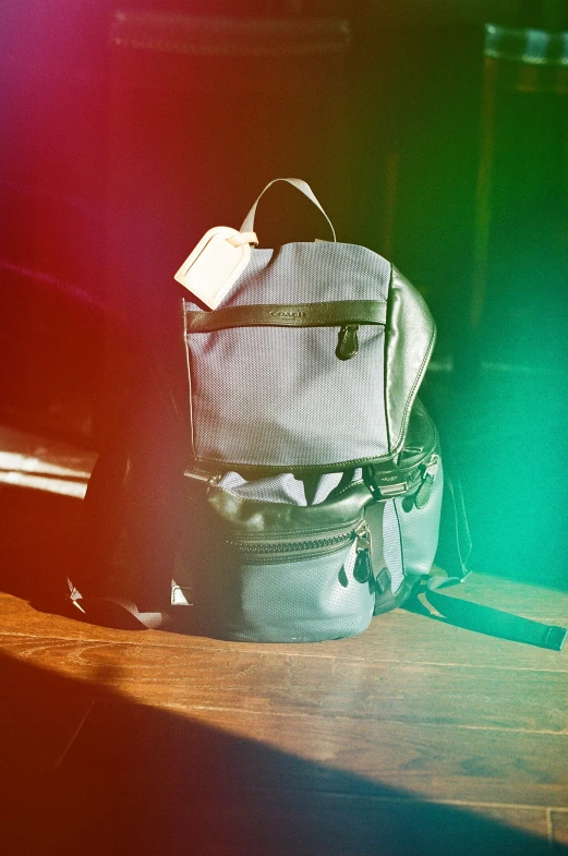 some different backpacks sitting on the floor by themselves