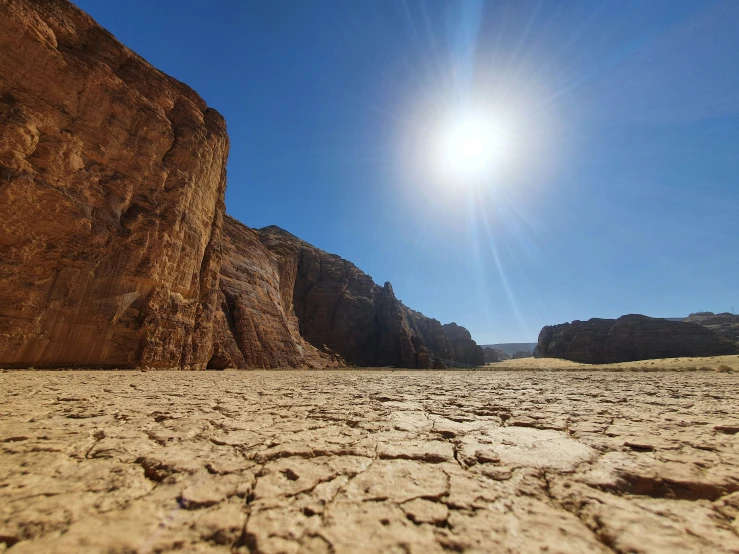 a bright sunny sun shines behind large rocks