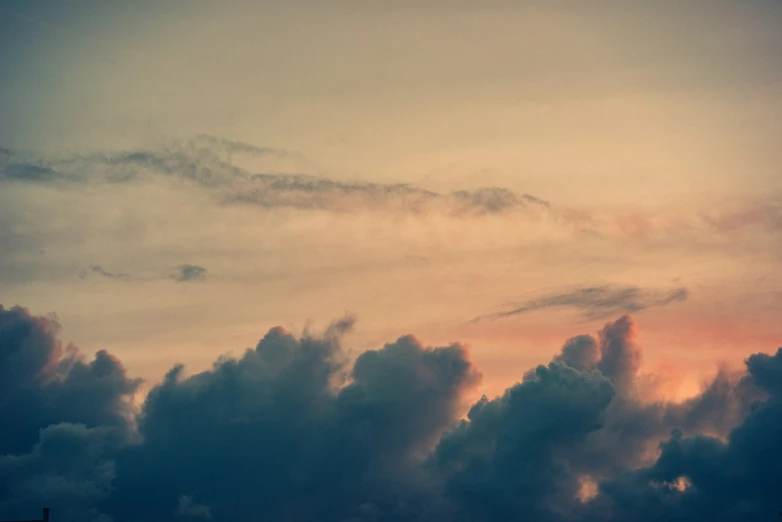 a plane flies through the clouds at sunset