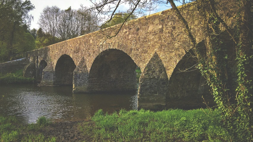 old stone bridge over a river surrounded by trees