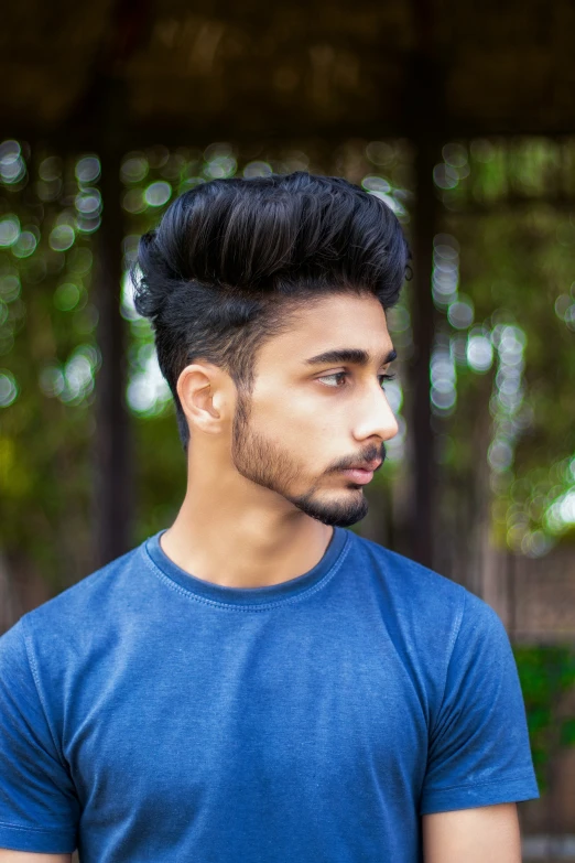 a young man with a beard standing outside