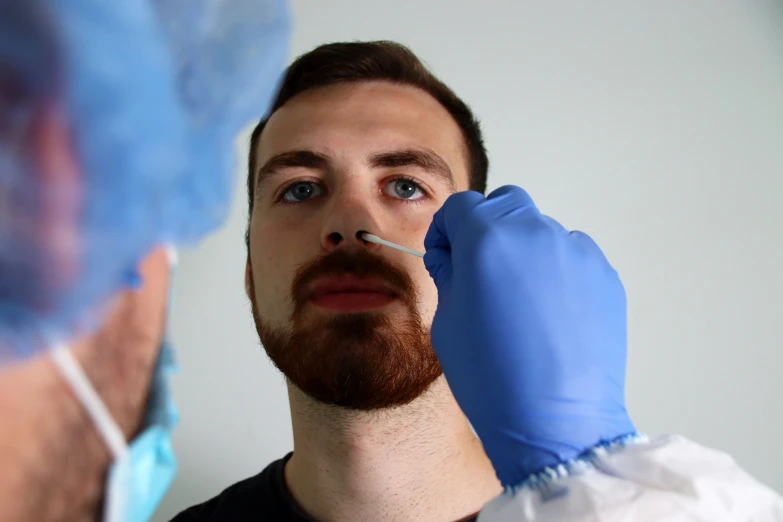 a male is wearing sterile blue gloves to clean his face