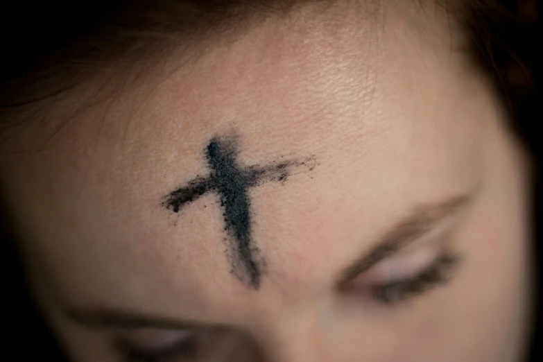 a person's eye is covered in a cross tattoo