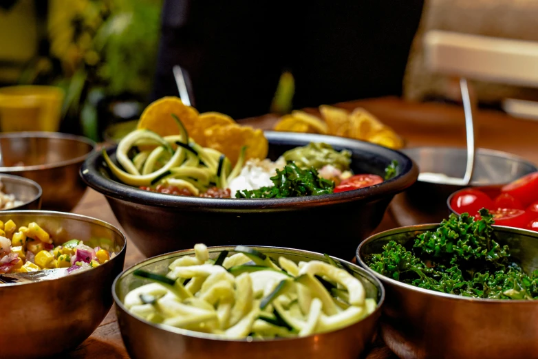 various bowls containing pasta are displayed on a wooden table