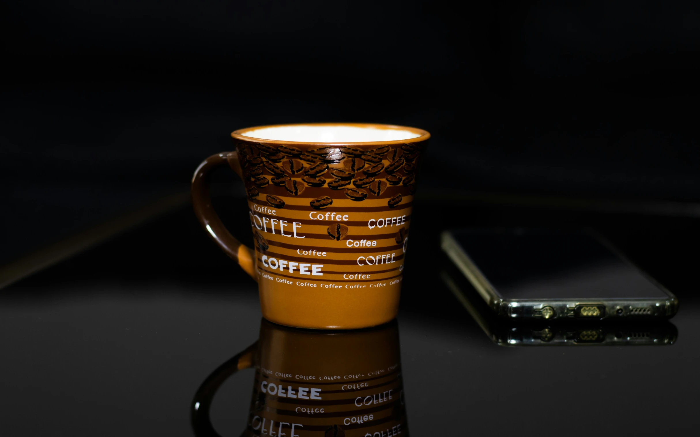 a coffee mug on a table with a cell phone in the background