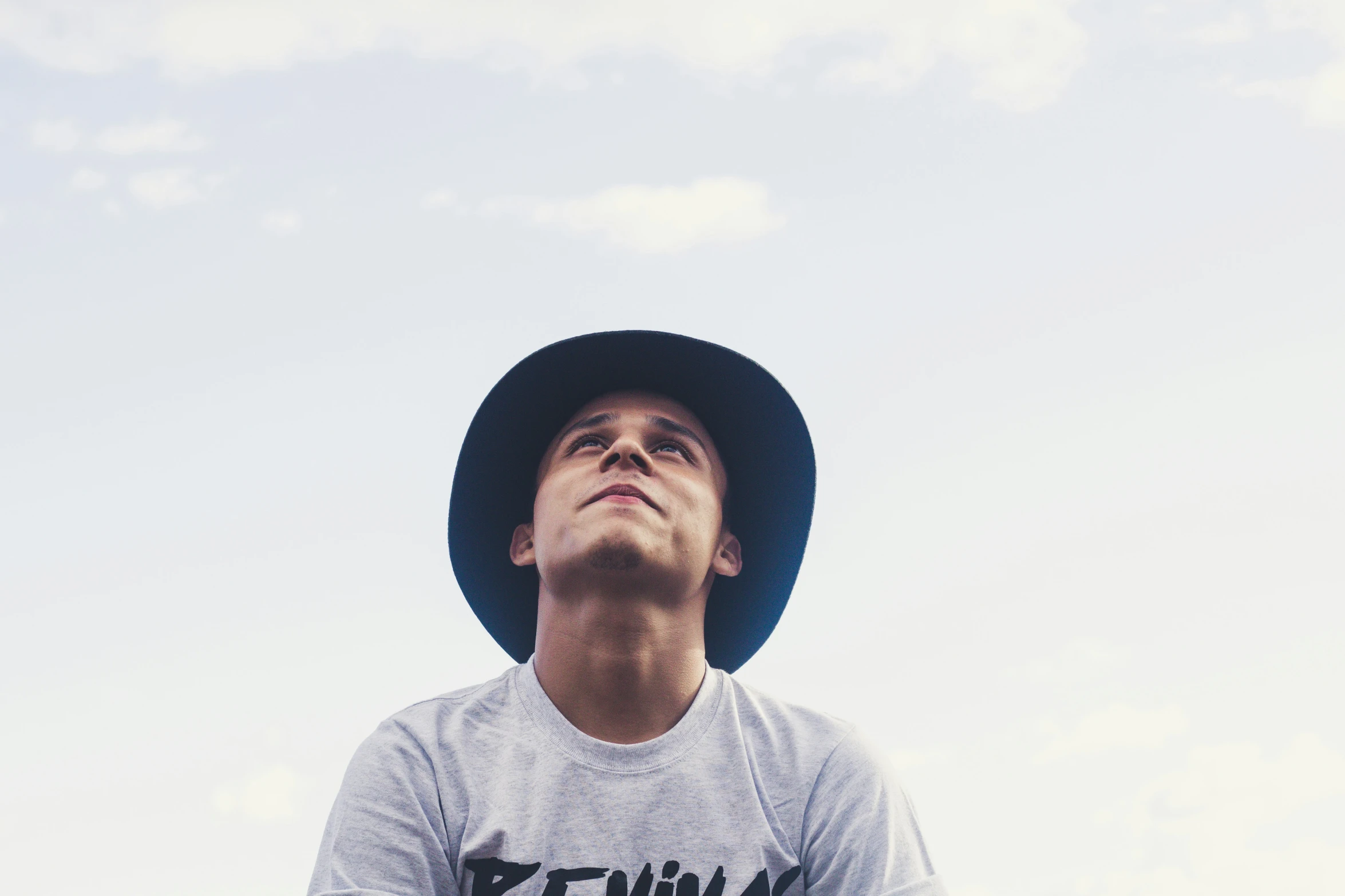 a boy wearing a hat looking up at the sky