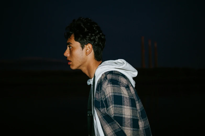 a young man standing in the dark looking away