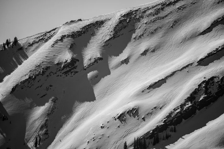 the snowy slopes of the mountain are barely covered with snow