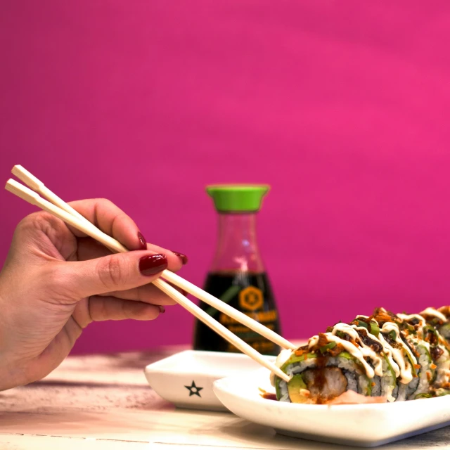 someone holding chopsticks in front of a plate of sushi