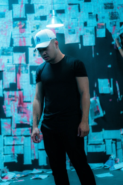 man on skateboard standing in front of a blue wall