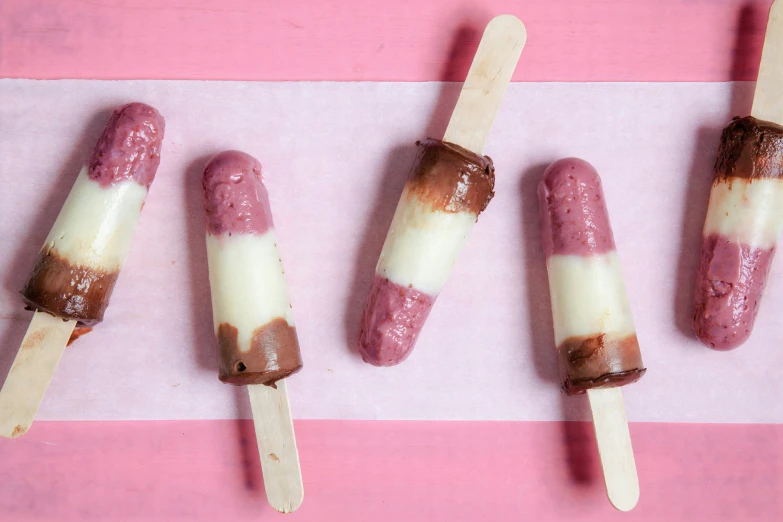 four food on sticks that are placed on a pink and white striped background