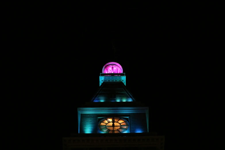 a steeple at night lit up with a lit up window