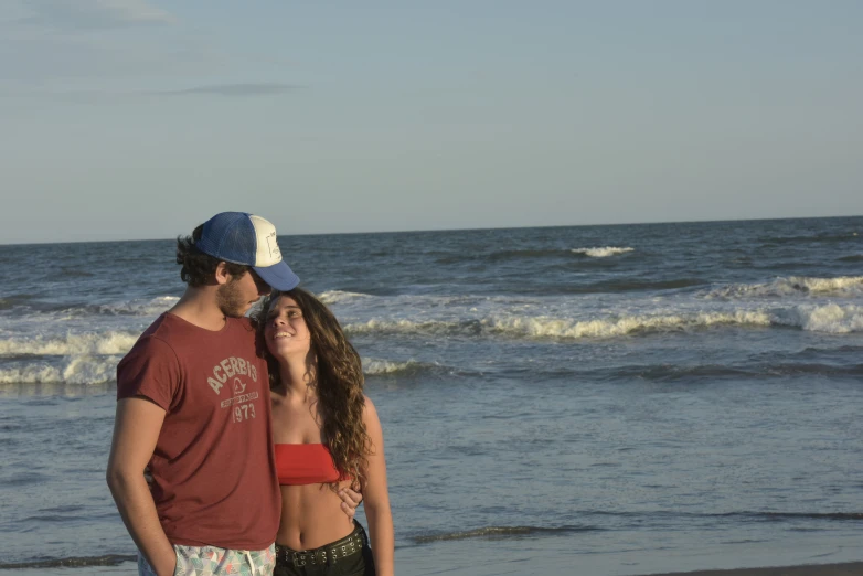 the man is next to a young woman while they stand close to the ocean