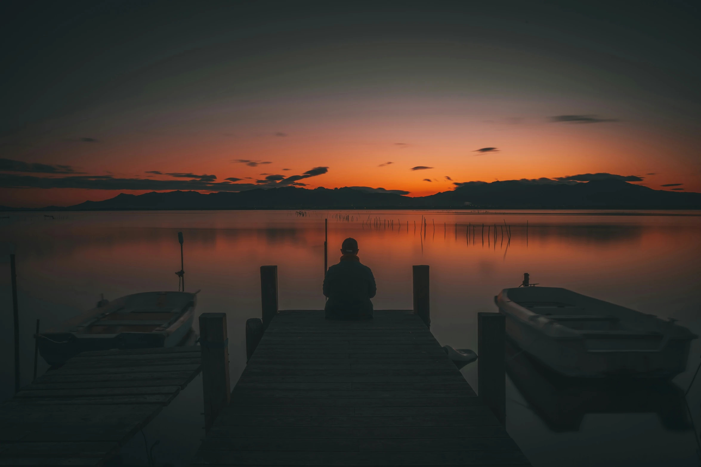 a man sitting on a dock at sunset