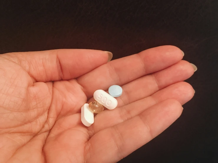 a person holding three pills in their hand