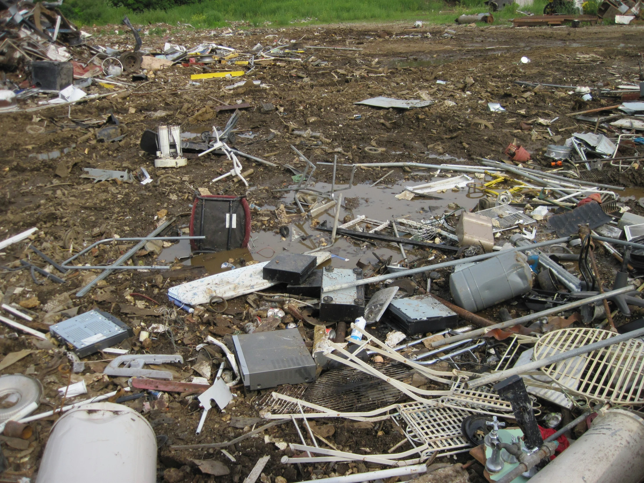 a pile of electrical debris sitting on top of a dirty field