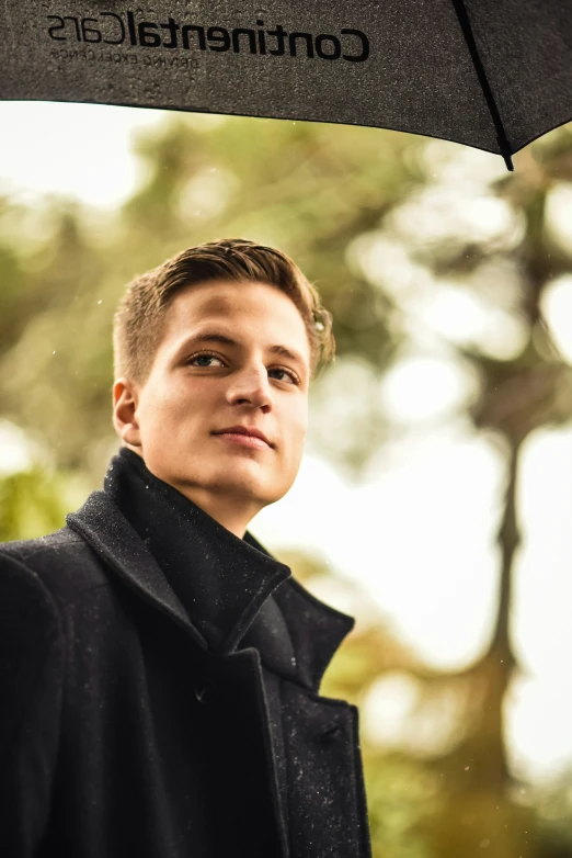 a man in a black suit is underneath a black umbrella