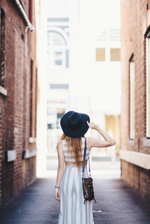 a young woman with red hair wears a striped dress and black floppy hat