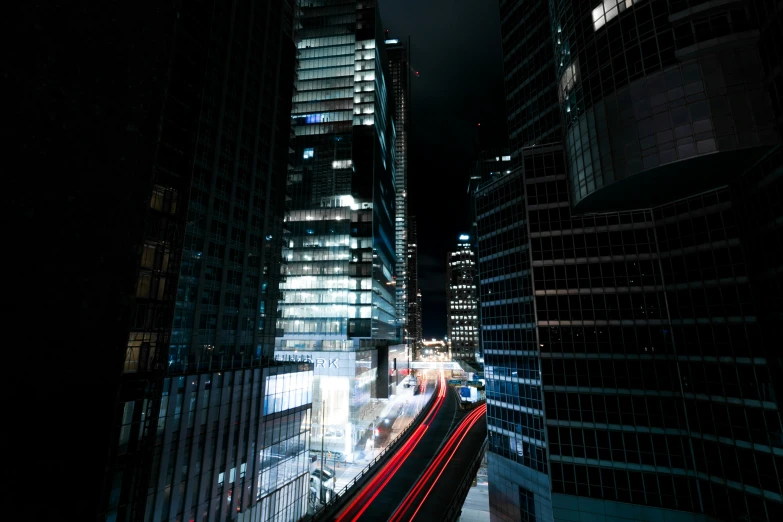 a city street at night with high rise buildings in the distance