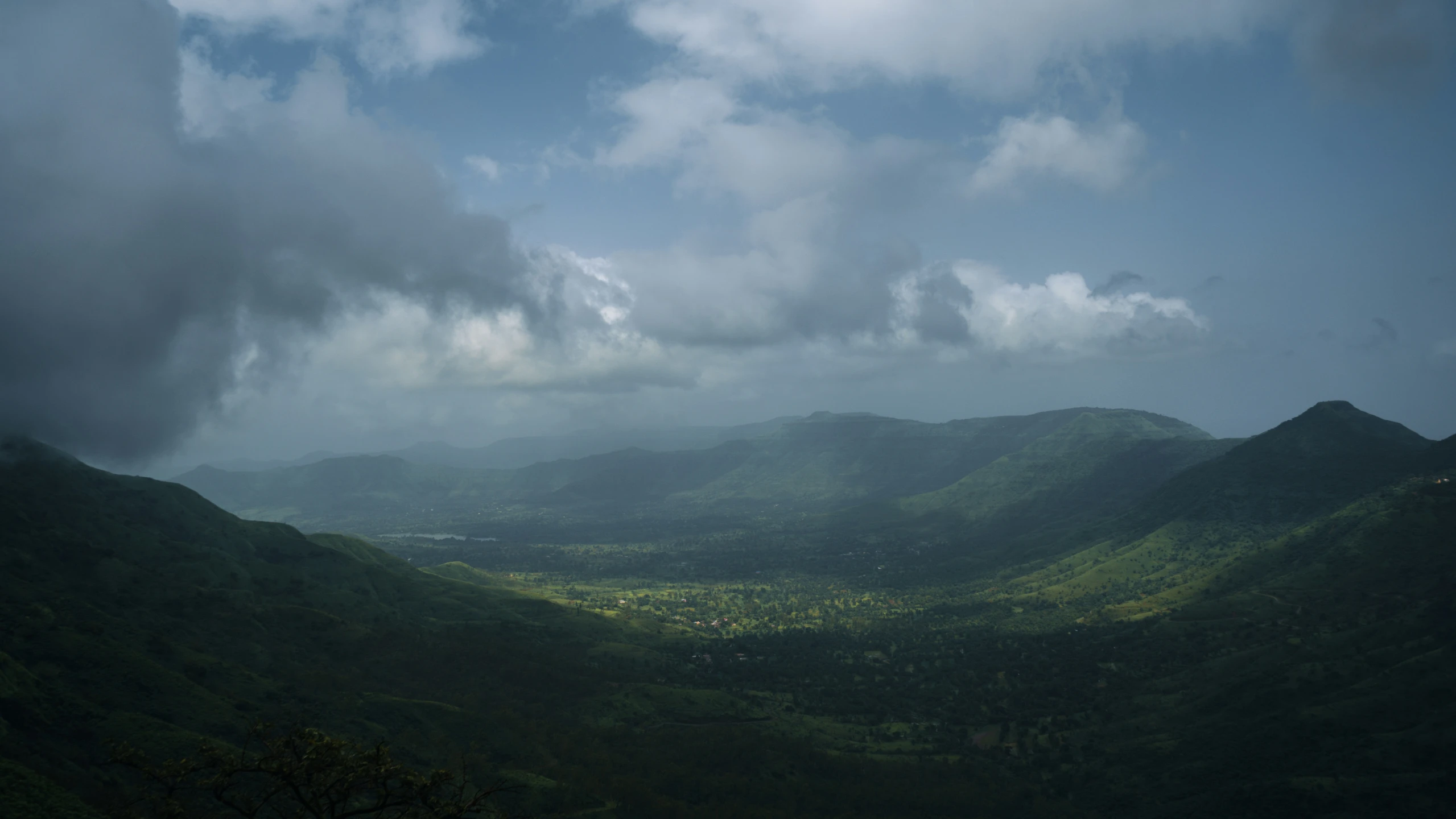 storm clouds cover the mountains and lush green vegetation