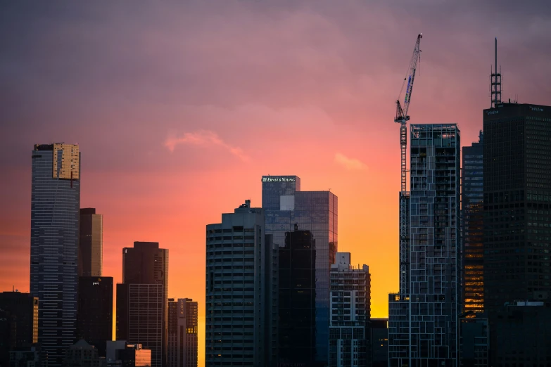 a very tall city skyline with the sky in red and yellow