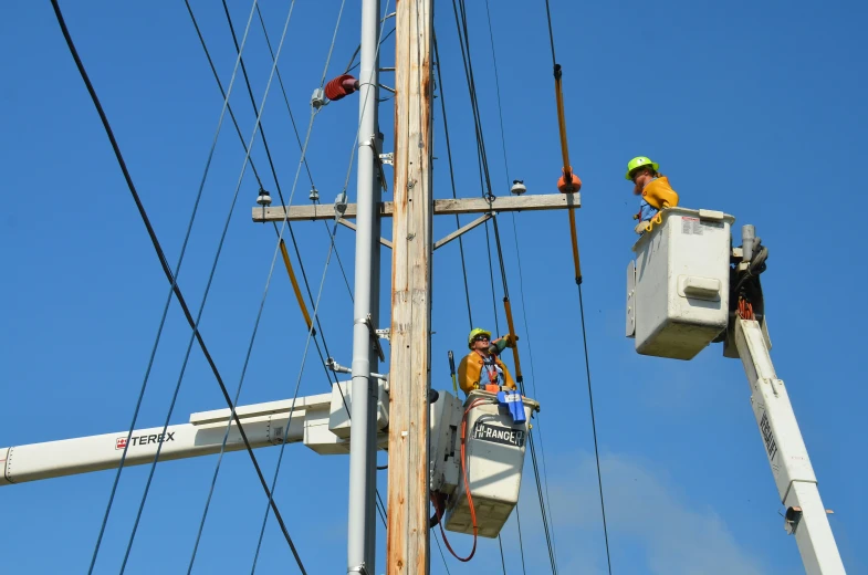 electric workers are using their buckets to repair power