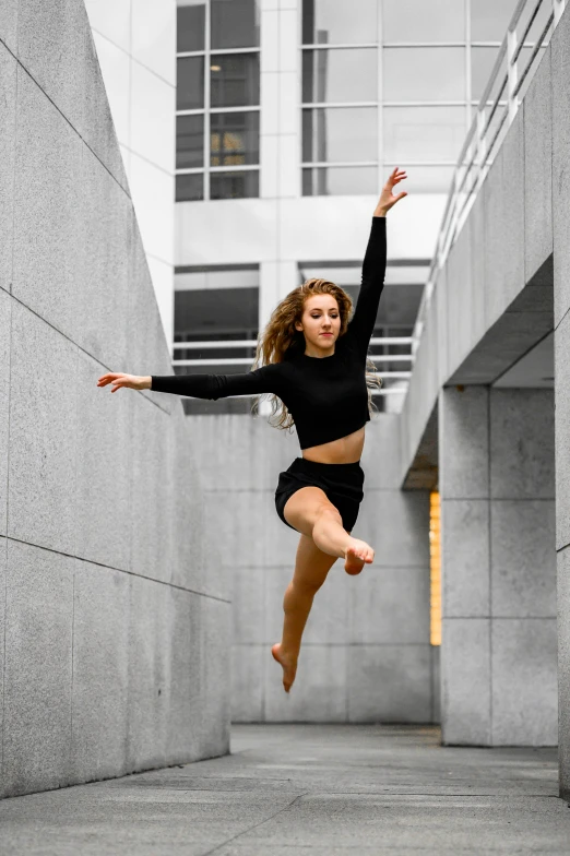 a young woman jumps in the air wearing black clothing
