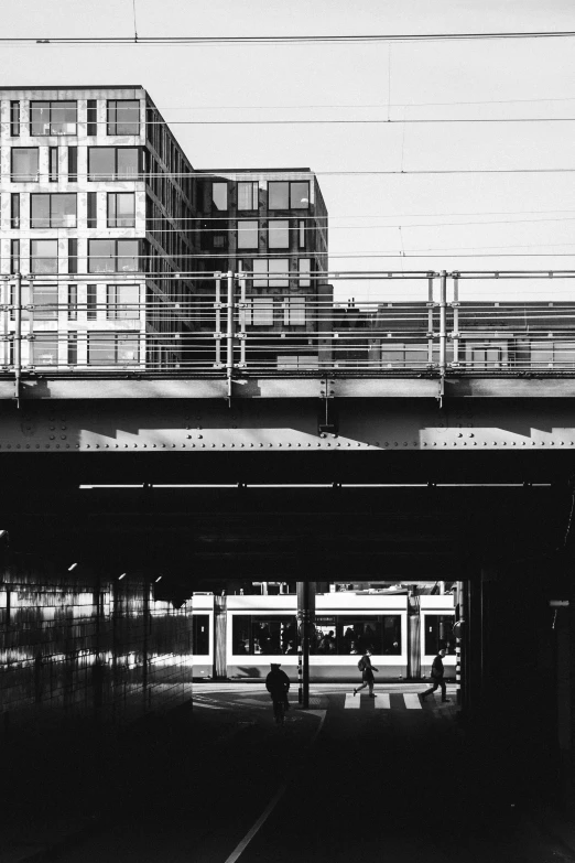 people walking underneath a bridge in the evening