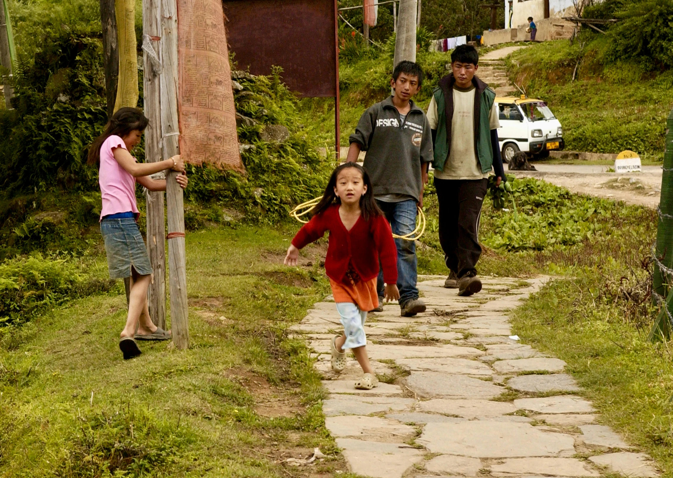 two children, a woman and a man are walking down a path