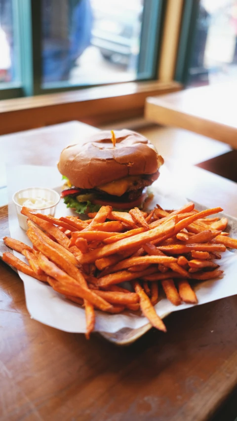 a burger with cheese is sitting on a plate with french fries