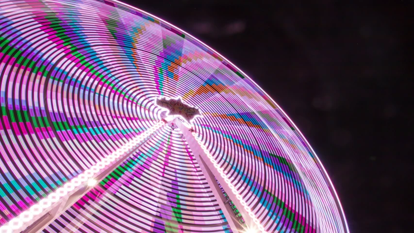 a bright ferris wheel with rainbow lights lite up
