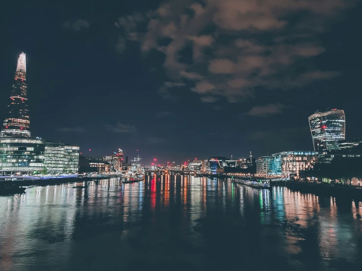 night time cityscape on a river, lights reflecting off of water