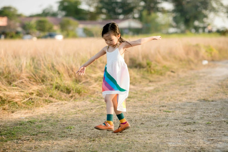 a girl in a dress and socks walking through a field