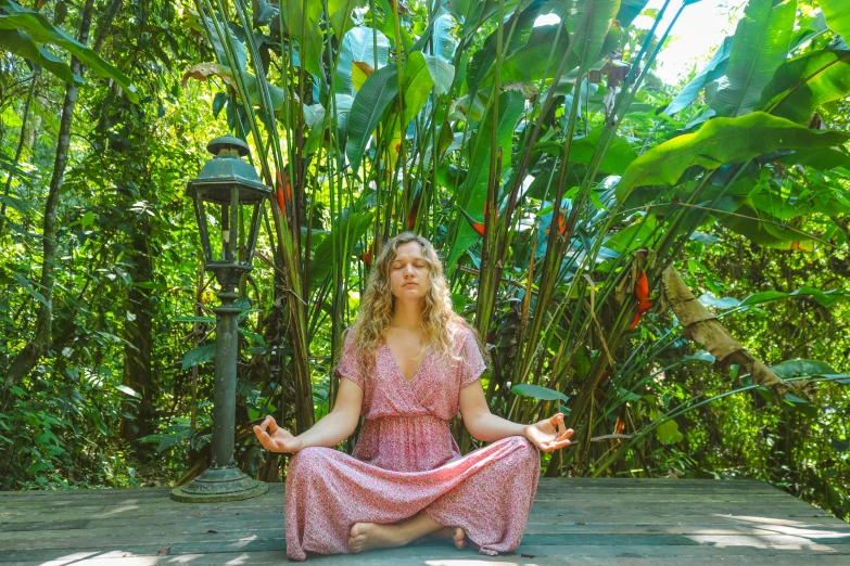 a woman is meditating in a garden and smiling