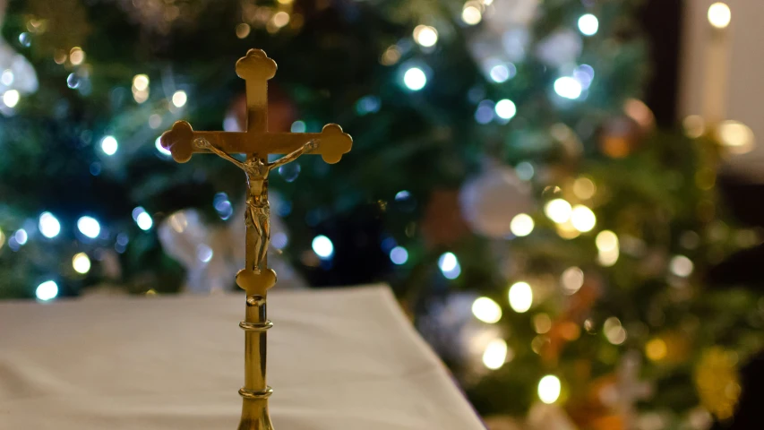 a crucifix with an illuminated christmas tree in the background