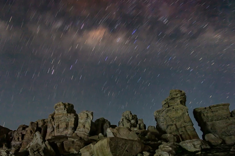 an image of the night sky over rocks