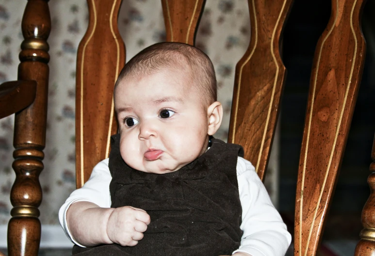 a baby sitting in a wooden rocking chair