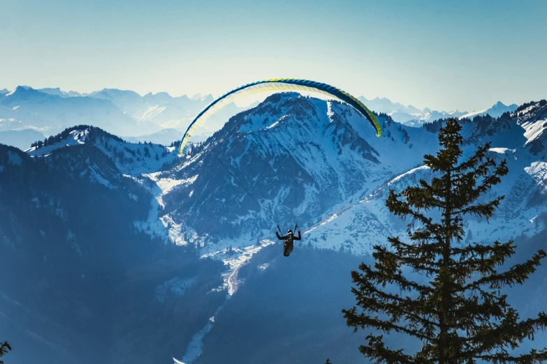 paraglider over snowy mountains with mountains in the background