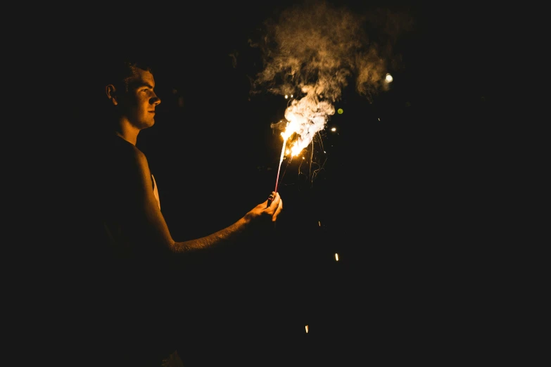 a young man holding out sparklers while looking at the camera