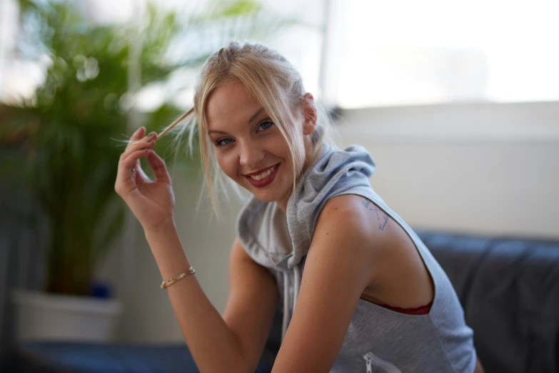 a young blond woman smiles as she holds an electronic cigarette